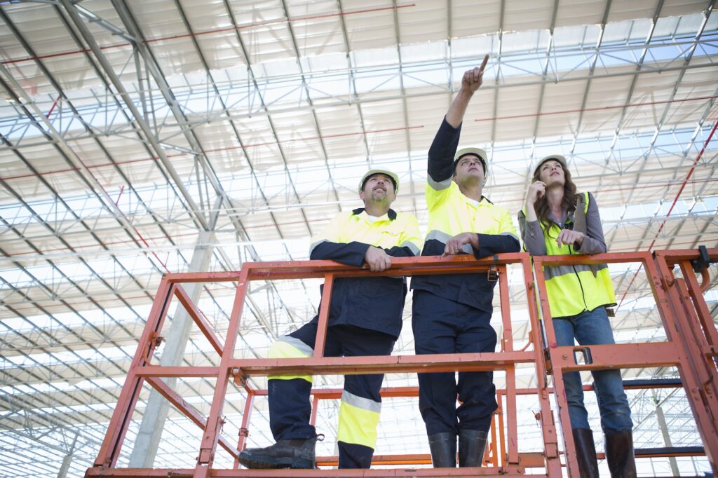 Low angle view of site managers and architect pointing from viewing platform on construction site
